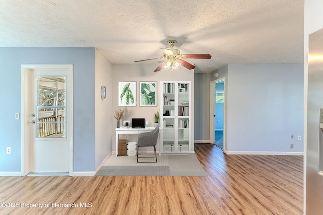 unfurnished office featuring baseboards, wood finished floors, a textured ceiling, and ceiling fan
