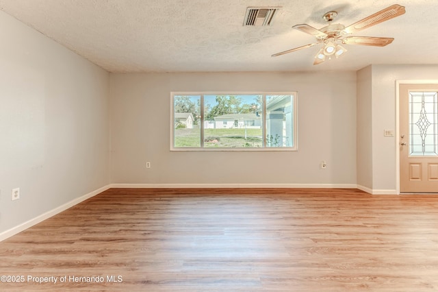 spare room with visible vents, a textured ceiling, light wood-type flooring, and baseboards