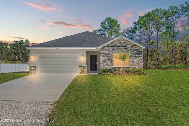 ranch-style house with fence, a yard, stucco siding, a garage, and stone siding