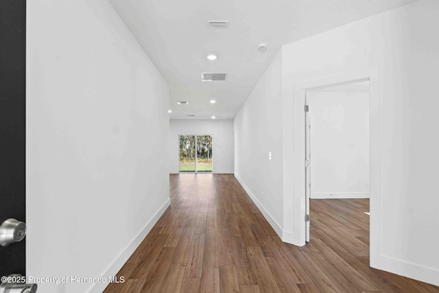 hallway with visible vents, recessed lighting, baseboards, and wood finished floors