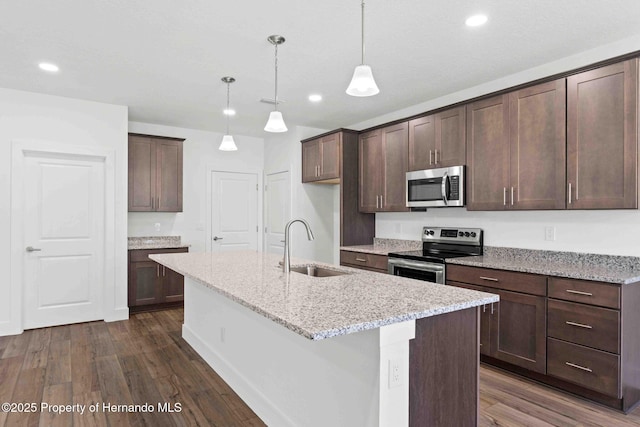 kitchen featuring dark wood-style floors, appliances with stainless steel finishes, an island with sink, and a sink