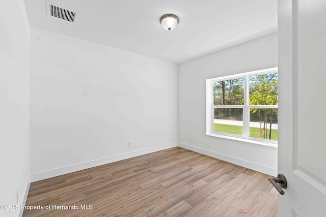 unfurnished room with visible vents, baseboards, and wood finished floors