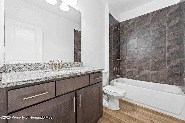 bathroom featuring vanity, toilet, wood finished floors, and tub / shower combination