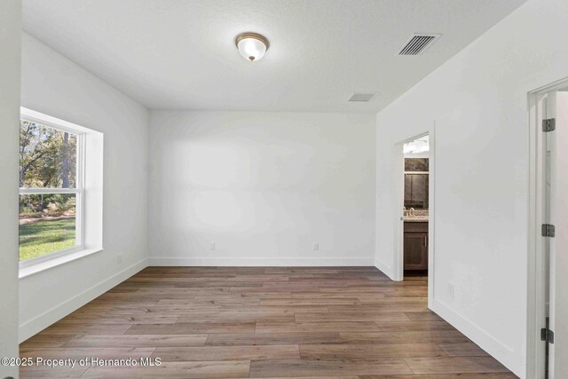 unfurnished room with visible vents, baseboards, and wood finished floors