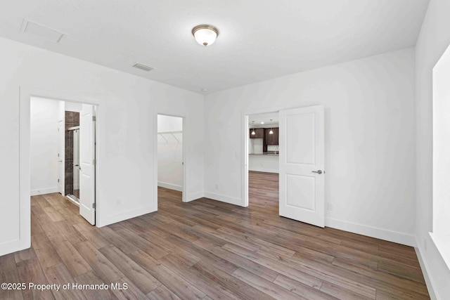 spare room featuring visible vents, baseboards, and wood finished floors