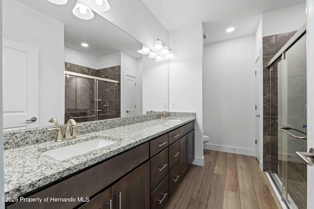 full bathroom with double vanity, a shower stall, toilet, and a sink