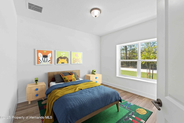 bedroom featuring wood finished floors, visible vents, and baseboards