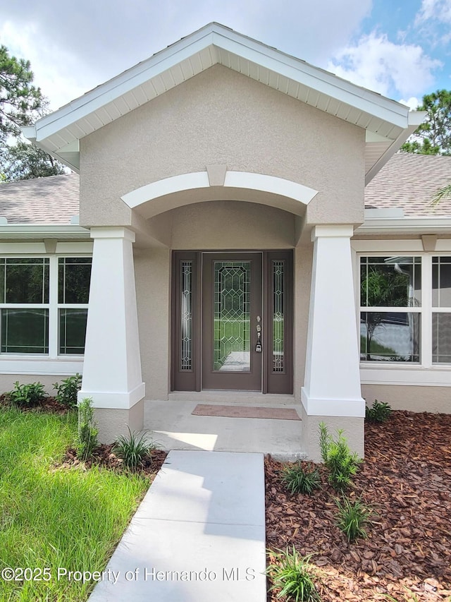 property entrance featuring stucco siding and roof with shingles