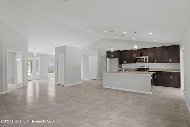 kitchen featuring a kitchen island with sink, a sink, stainless steel appliances, dark brown cabinetry, and open floor plan