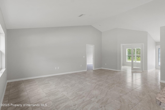 empty room with lofted ceiling, visible vents, and baseboards