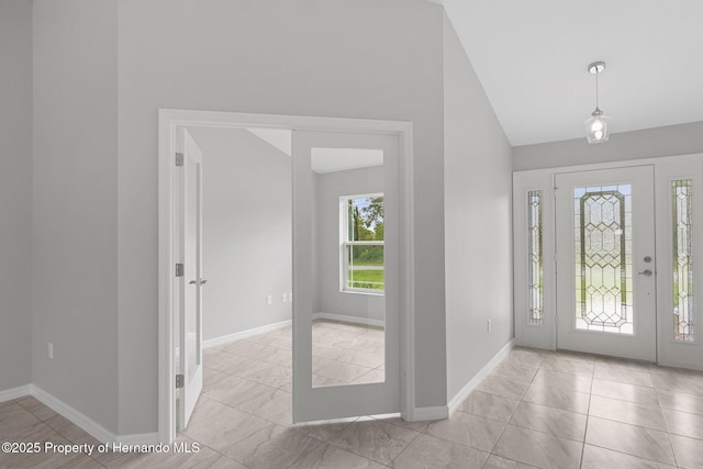 foyer entrance featuring lofted ceiling and baseboards