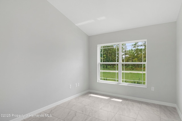 unfurnished room featuring lofted ceiling and baseboards