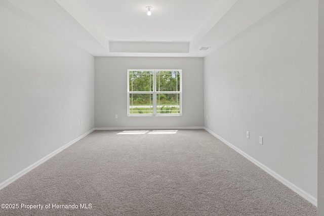 carpeted empty room featuring baseboards and a tray ceiling