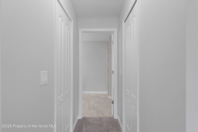 hallway with baseboards and carpet