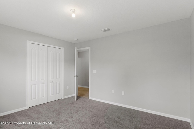 unfurnished bedroom featuring visible vents, baseboards, a closet, and carpet flooring