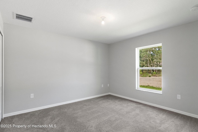 carpeted empty room featuring visible vents, a textured ceiling, and baseboards