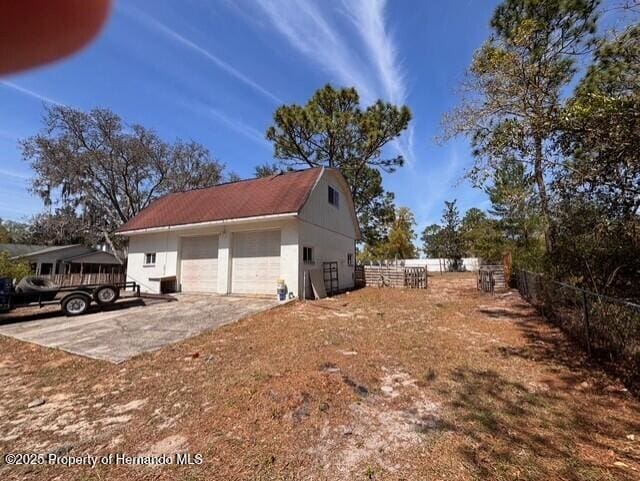 view of side of property with a detached garage, an outdoor structure, and fence