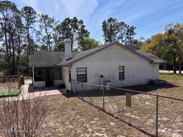 back of house featuring fence and a chimney