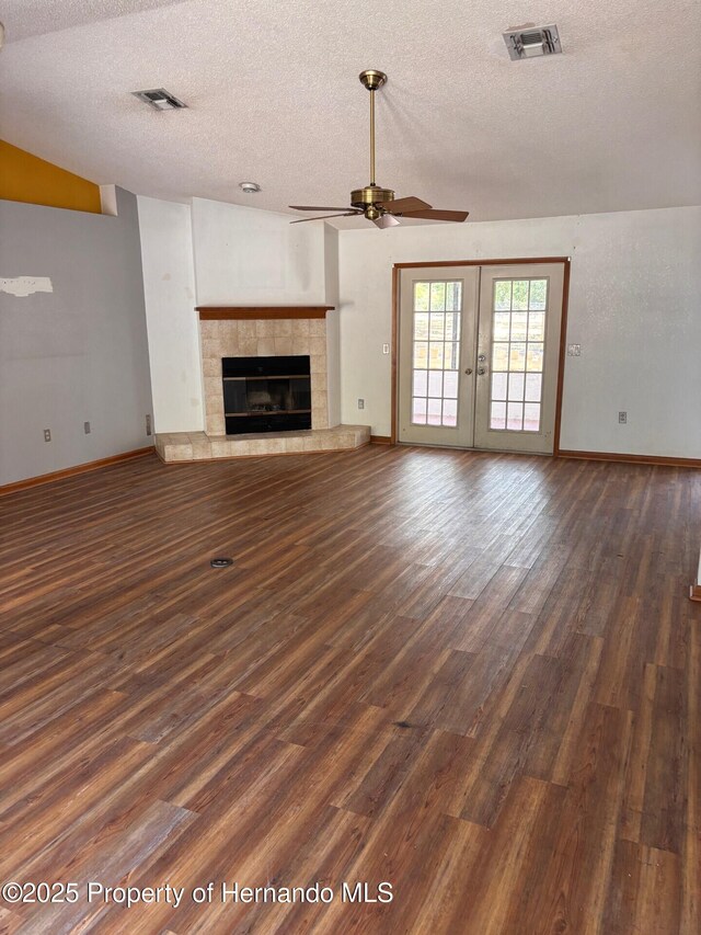 13935 Linden Dr, Spring Hill, FL 34609 - unfurnished living room with visible vents, dark wood-style flooring, ceiling fan, a textured ceiling, and a tiled fireplace