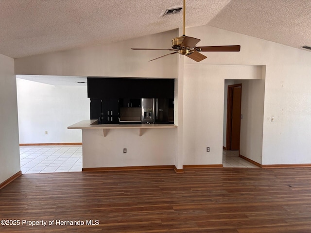 13935 Linden Dr, Spring Hill, FL 34609 - unfurnished living room with a textured ceiling, a ceiling fan, baseboards, wood finished floors, and vaulted ceiling