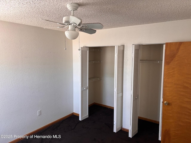13935 Linden Dr, Spring Hill, FL 34609 - unfurnished bedroom with two closets, dark carpet, baseboards, ceiling fan, and a textured ceiling