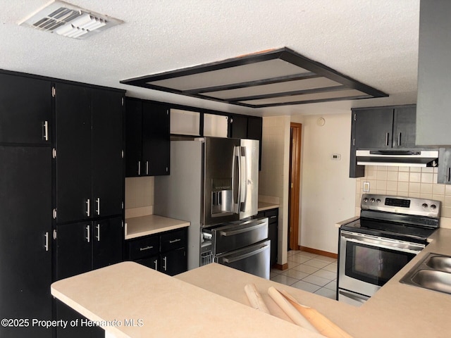 13935 Linden Dr, Spring Hill, FL 34609 - kitchen with a textured ceiling, under cabinet range hood, tasteful backsplash, dark cabinets, and stainless steel appliances