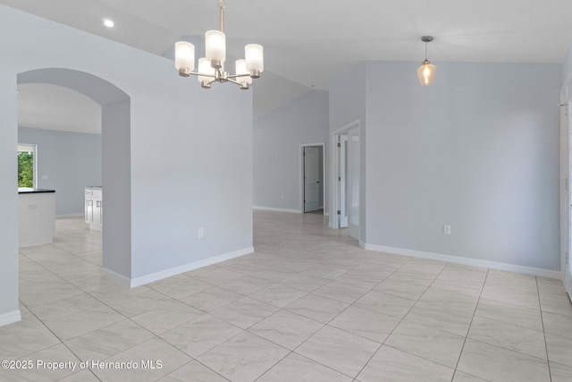 empty room featuring light tile patterned floors, baseboards, lofted ceiling, arched walkways, and a notable chandelier