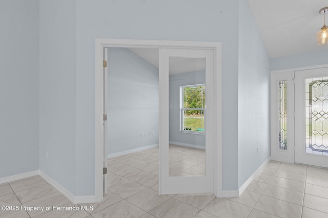 foyer with baseboards and vaulted ceiling