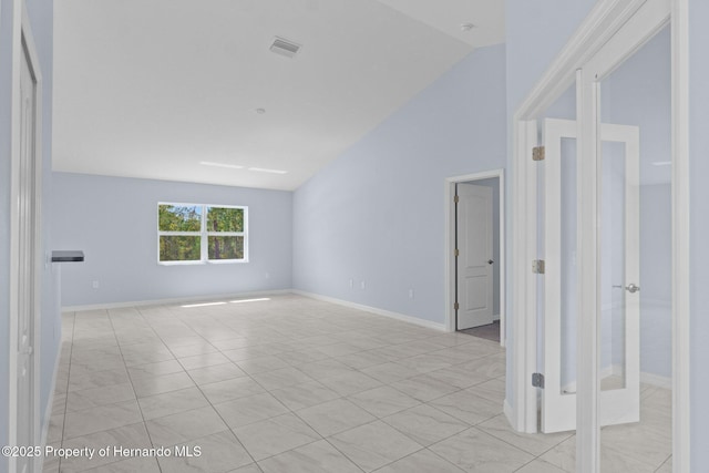 empty room featuring visible vents, baseboards, and lofted ceiling