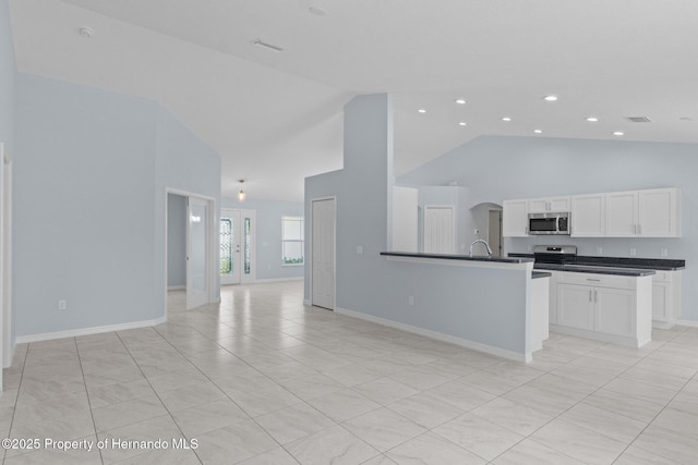 kitchen with dark countertops, visible vents, open floor plan, white cabinets, and stainless steel appliances