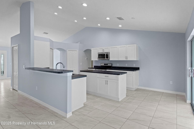 kitchen featuring visible vents, a peninsula, arched walkways, stainless steel appliances, and white cabinetry