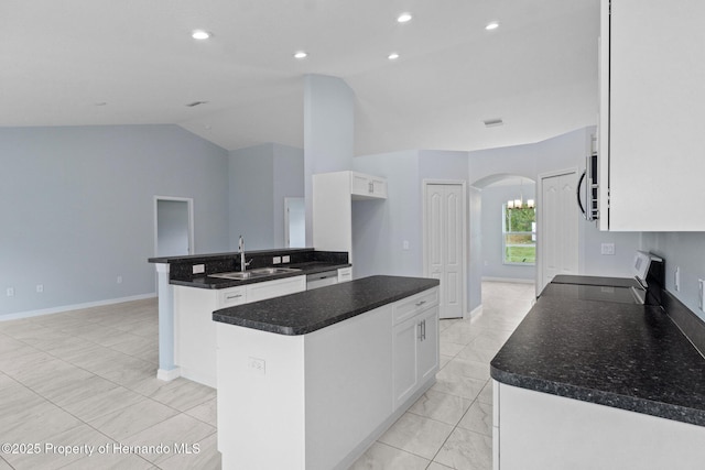 kitchen with a sink, vaulted ceiling, arched walkways, white cabinetry, and range