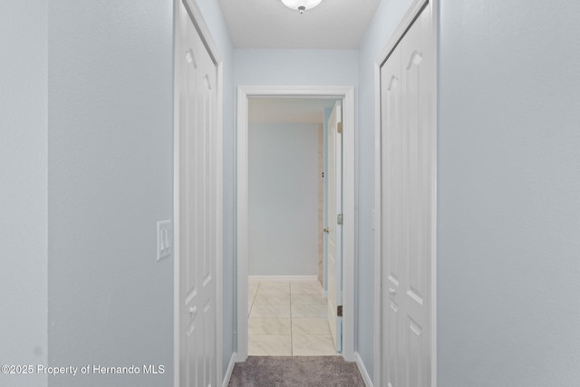 hall featuring light colored carpet and baseboards