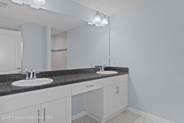 bathroom with double vanity, baseboards, visible vents, and a sink