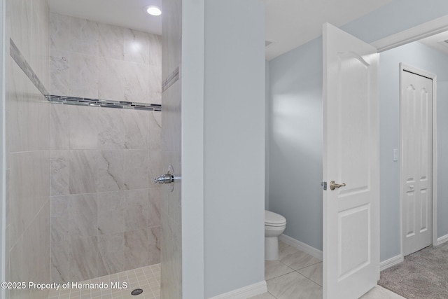 full bathroom with tiled shower, toilet, and baseboards