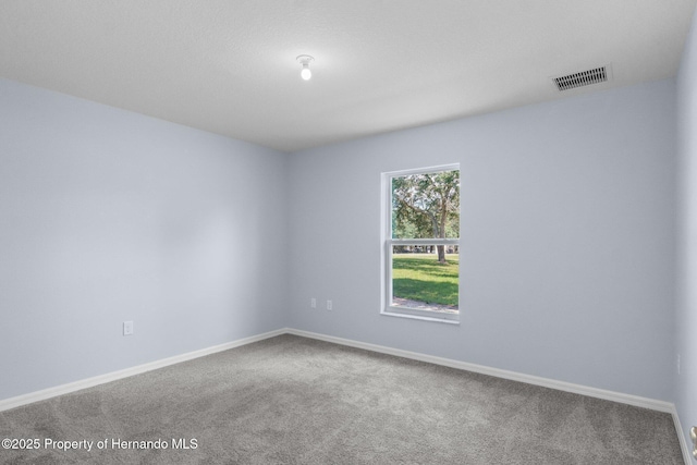 carpeted spare room featuring visible vents and baseboards