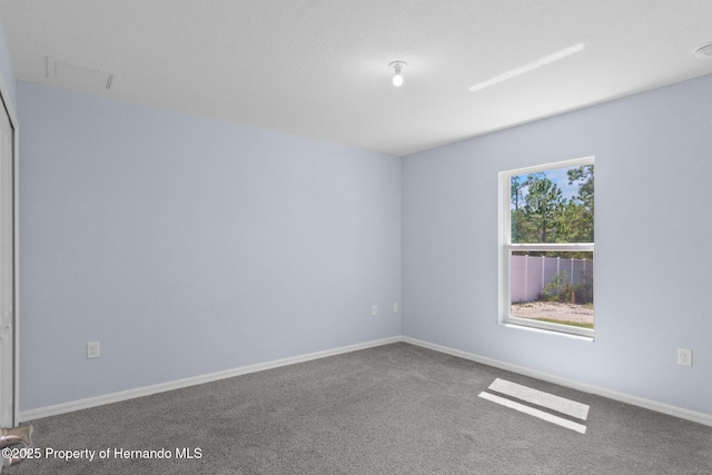 carpeted spare room with visible vents and baseboards