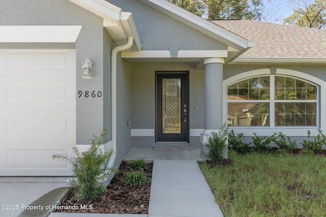 doorway to property featuring a shingled roof, a garage, and stucco siding