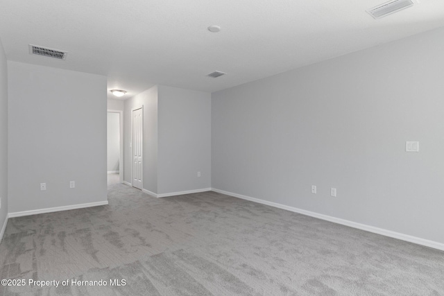 carpeted spare room featuring baseboards and visible vents