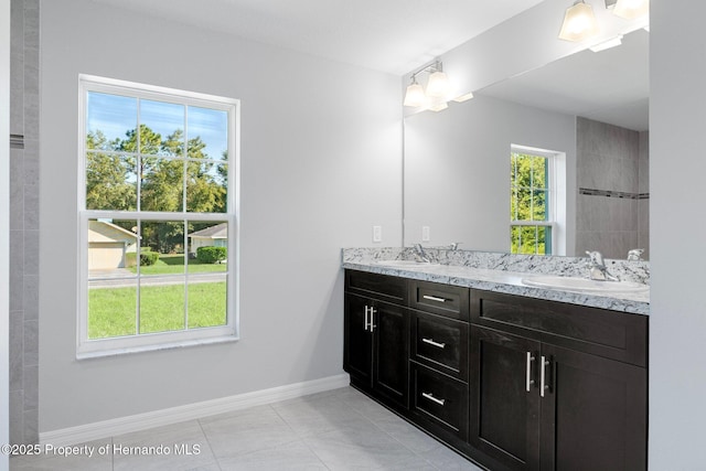 bathroom with double vanity, tile patterned floors, baseboards, and a sink