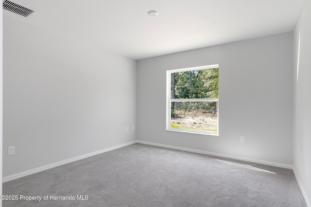 carpeted spare room with visible vents and baseboards