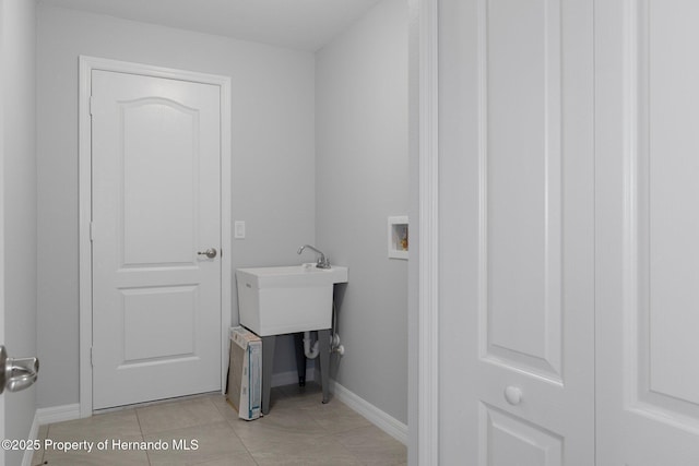 washroom with light tile patterned floors, baseboards, hookup for a washing machine, and laundry area