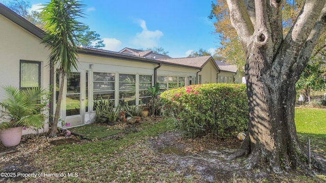 view of side of home with stucco siding and a sunroom