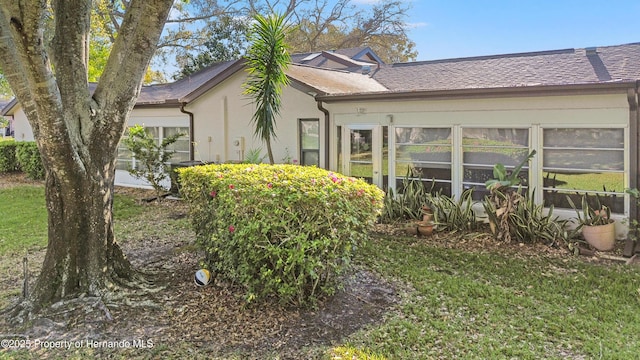 view of property exterior with a shingled roof, a yard, and stucco siding