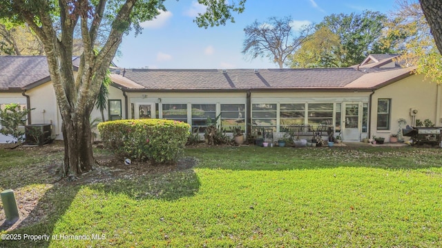 rear view of property with stucco siding, a lawn, and cooling unit