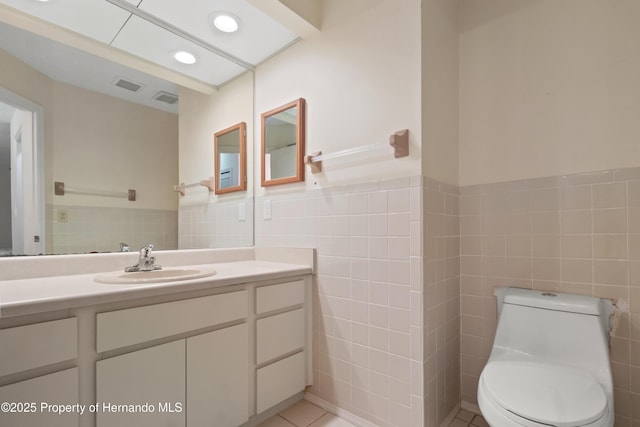 bathroom featuring tile patterned flooring, toilet, vanity, recessed lighting, and tile walls