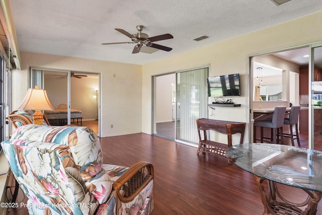 living area with wood finished floors, a ceiling fan, visible vents, and a textured ceiling