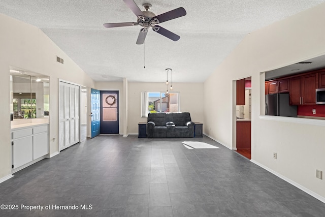 unfurnished living room featuring a textured ceiling, vaulted ceiling, and ceiling fan