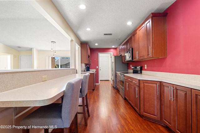 kitchen with visible vents, a textured ceiling, dark wood-style floors, stainless steel appliances, and light countertops