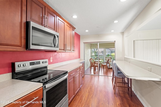 kitchen featuring light wood-type flooring, light countertops, recessed lighting, stainless steel appliances, and a textured ceiling